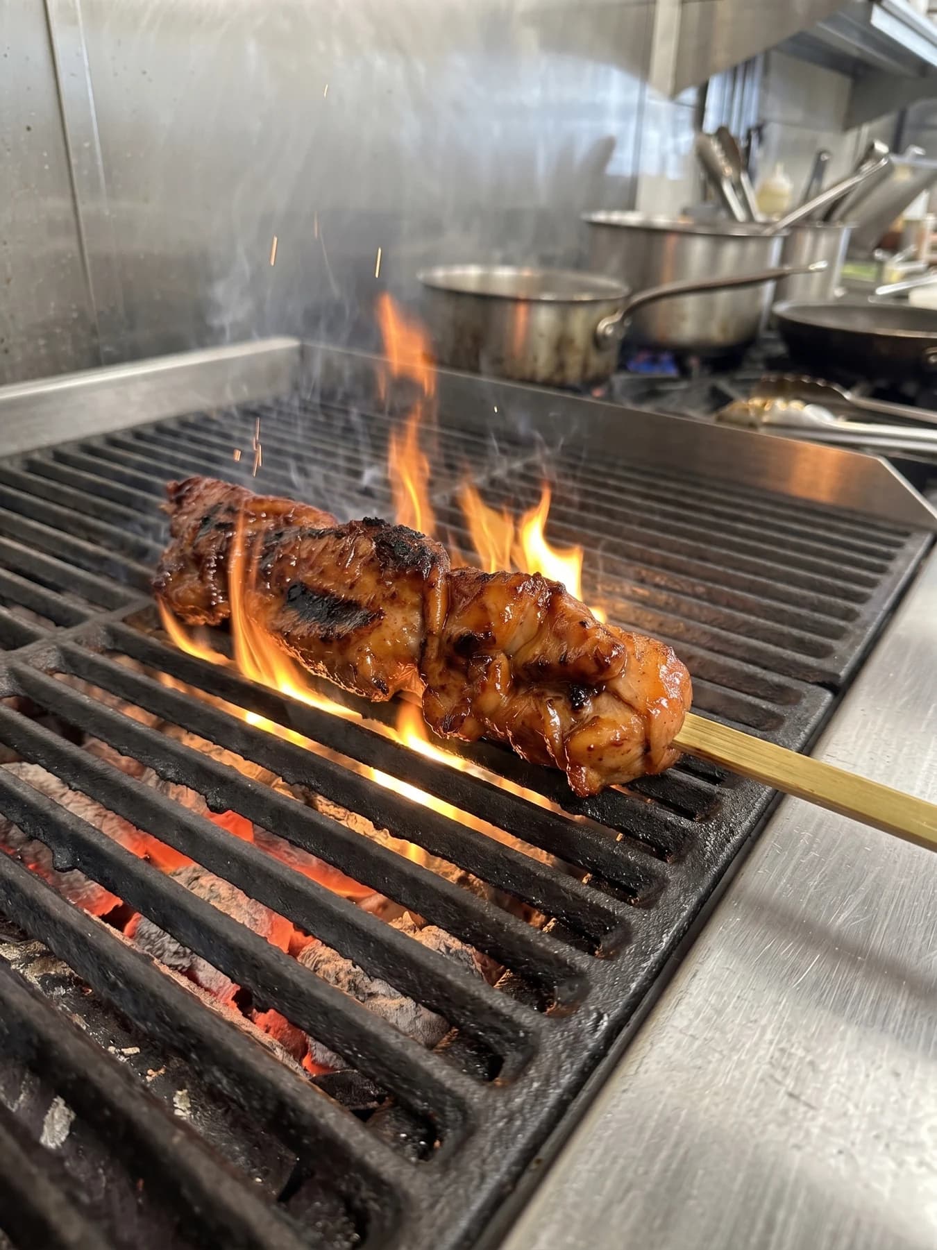 A whole chicken BBQ skewer cooking over flames on the grill